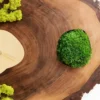 Close-up of tree slice clock showing natural wood grain, green ball moss inlay, and reindeer moss numerals