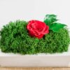 Rectangular concrete vase centerpiece arrangement featuring preserved moss and a rose on a wooden surface