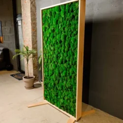 Tall wooden room divider with vibrant green textured moss, standing in a modern room.