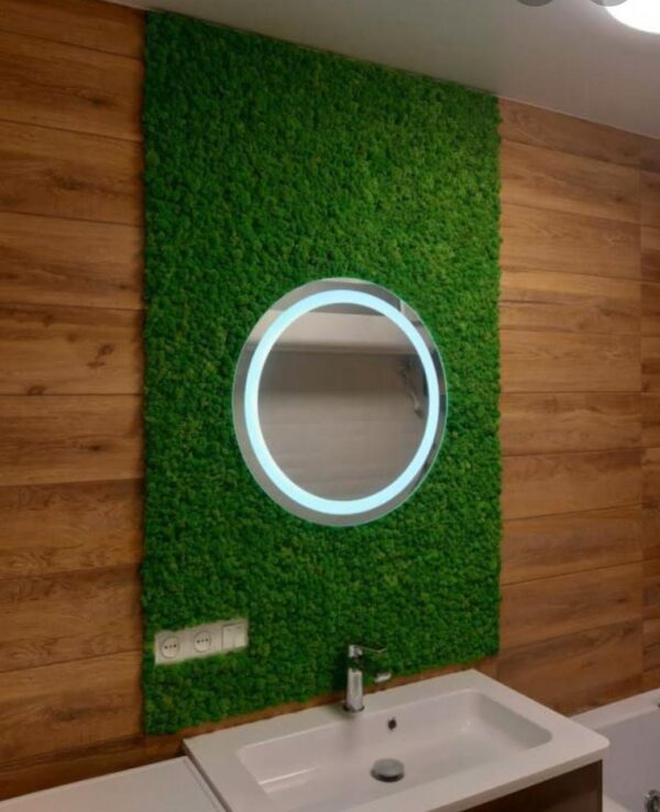 Round illuminated mirror embedded in a preserved moss wall panel above a bathroom vanity