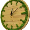 Round wooden wall clock with green moss inlay along the rim and hour markers, black hands, and a red second hand.