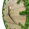 Round wooden wall clock with green moss inlaid around the rim and black clock hands.
