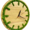 Round wooden wall clock with green moss inlaid along the outer rim to mark the hours, with black and red hands.