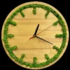 Round wooden wall clock with green moss inlaid around the rim to mark hours, with black and red hands.
