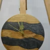 Front view of round wood clock featuring dark gray resin rivers and ornate gold hands on a wooden stand (9 in)