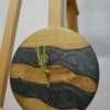 Round wood wall clock with dark gray swirling epoxy river bands and gold hands, displayed on an easel (9 in)