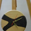 Round wood wall clock (9") with black swirl epoxy resin inlay, ornate gold hands, and red second hand on an easel