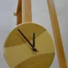 Round wood wall clock with cream epoxy resin river, black and red hands, resting on wooden easel (9" / 23 cm)