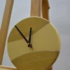 Round wood and cream epoxy resin wall clock (9.0") with black hands displayed on a wooden easel.