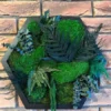 Hexagon moss wall art with preserved foliage and ball moss in a geometric frame mounted on a brick wall.