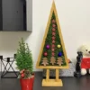 Triangular wooden Christmas tree decoration filled with stabilized moss and festive ornaments on a stand