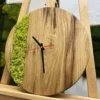 Round wood wall clock with light green moss inlay and black hands, displayed on a wooden easel.