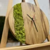 Angled view of a round wood wall clock with light green moss inlay, resting on a wooden easel.