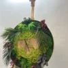 Angled view of round moss wall clock with wood slice center and mixed preserved plants displayed on wooden easel