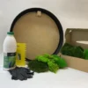 Round black frame DIY moss kit with glue bottle, yellow comb scraper, black gloves, and cardboard box with green moss
