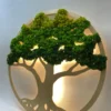 Angled view of round wooden tree wall art with textured green moss foliage and glowing warm backlight