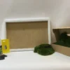 DIY moss wall art kit with white frame, boxed green moss, adhesive bottle, yellow trowel, and gloves