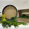 Round moss art kit components with black frame, open box of moss, preserved foliage, adhesive bottle, and spreader.