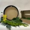 DIY moss art kit with round black wooden frame, glue bottle, spreader, gloves, ferns, and box of preserved moss.