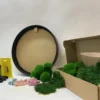 DIY moss kit materials with round black frame, assorted green preserved moss, colorful dried flowers, glue, and gloves.