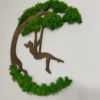 Angled view of round wooden wall art featuring a girl on a swing silhouette surrounded by green preserved moss