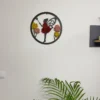 Round black fairy moss wall art hanging on a white wall above an indoor green palm plant.