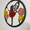 Round black wooden moss wall art with a fairy silhouette, red moss dress, and colorful moss flowers on a white wall.