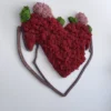 Angled view of textured red and pink reindeer moss heart framed in dark brown wood against a white wall.