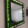 Side angle of square mirror with textured green ball moss and glowing LED backlighting in black wooden frame
