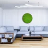 Round green reindeer moss wall art on a white wood-paneled wall above a sectional sofa in a living room