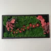 Preserved moss wall art with floral accents and foliage in a rectangular frame.