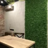 Rectangular preserved moss wall art installed on an interior wall beside a dining table.