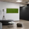 Horizontal green moss wall panel displayed above a curved lounge sofa in an office lobby.