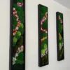 Angled view of three vertical black-framed moss panels with colorful dried flower accents on a white wall.