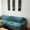 Three vertical moss wall art panels with black frames mounted on a white wall above a teal sofa.