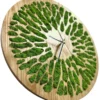 Angled view of round wood wall clock with decorative cutouts inlaid with green preserved moss.