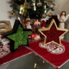 Black and natural wooden Christmas stars filled with green and red moss sitting on red festive mats.