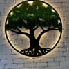 Black circular moss tree wall art with warm halo backlighting mounted on a white brick wall
