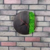 Round burnt wood wall clock with vibrant green moss accent, mounted on a brick wall