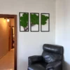 3-piece green moss tree wall art with cork wood in black frames, mounted on a white wall above a black leather chair.