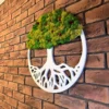 Angled view of round white wooden tree of life wall art with green preserved moss on an exposed brick wall