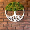 Front view of round white wooden tree of life wall art with textured green moss hanging on an exposed brick wall