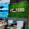 Green ball moss accent wall panel with 3D letters in a modern lounge area.