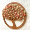 Circular wooden tree frame filled with textured pink and beige preserved moss, mounted on a white textured wall.