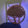 Backlit round wooden moss tree wall art glowing with purple LED light, resting on a chair