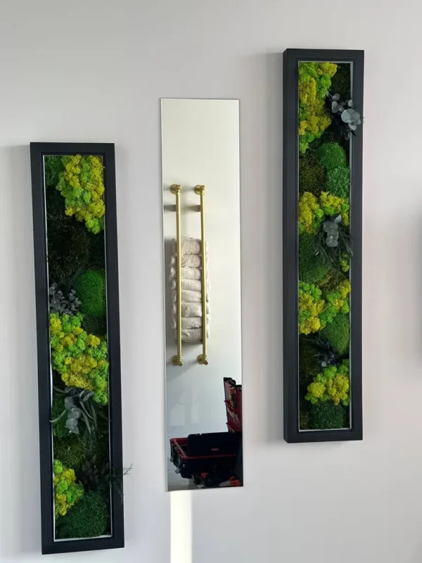 Two black-framed vertical moss art pieces with bright green and dark green moss, accented by grey foliage, on a light wall.