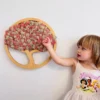 Child touching round wooden sakura tree art with pink and beige preserved moss on a white wall
