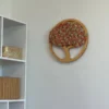 Round wooden tree wall decor with pink and beige moss, mounted on a white wall next to a white bookshelf.