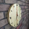 Side view of round maple wood and pearlescent epoxy wall clock mounted on an exposed brick wall