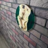 Side view of round maple wood and emerald green epoxy resin wall clock with Roman numerals mounted on brick wall